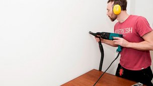 Mand borer hul i væg