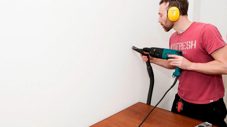 Mand borer hul i væg