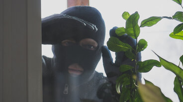 maskeret mand ser ind gennem vindue i bolig