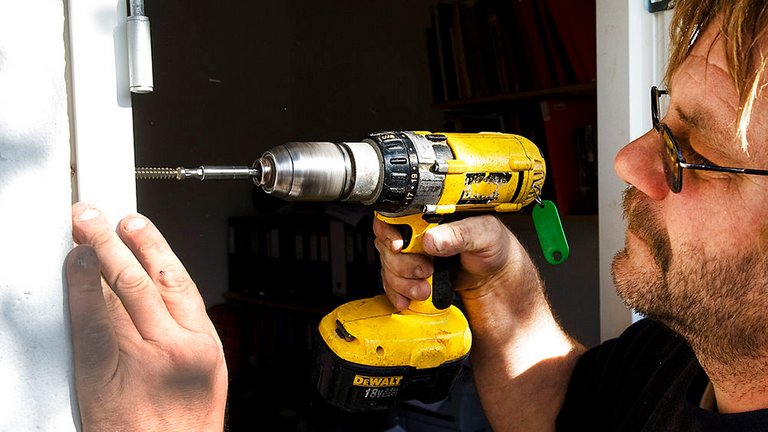 Håndværker montererer nyt vinduer. Håndværkeres og deres arbejde kan anmeldes hos Anmeld Håndværkere og Trustpilot