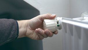 Nærbillede af person, der skruer på termostat