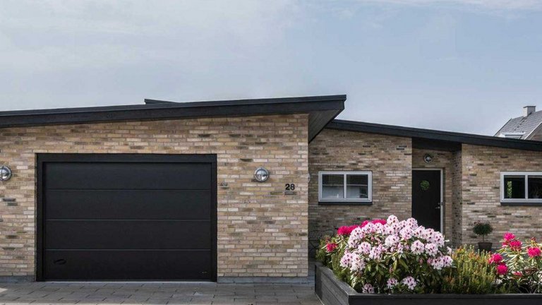 Sort ledhejseport i garage med samme mursten som hus