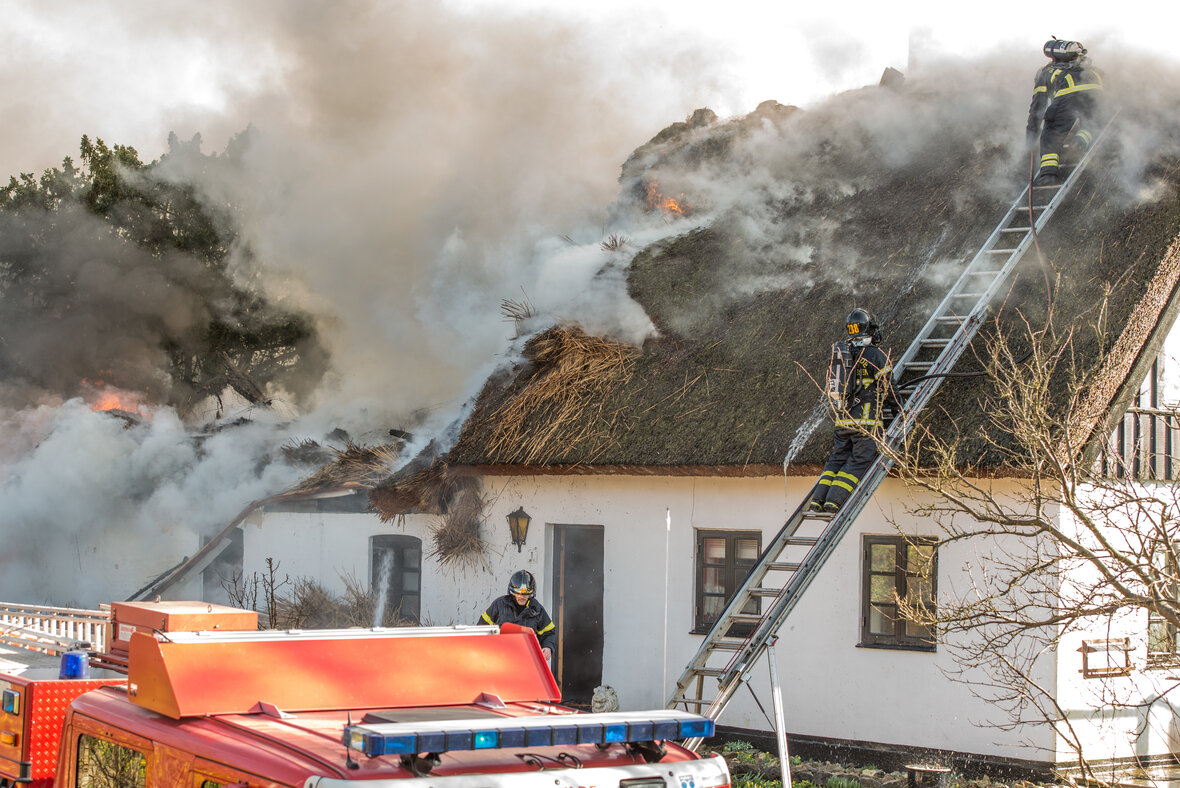 brandmænd slukker brand i stråtag på hus