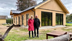 Mand og kvinde står foran nybygget træhus