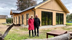 Mand og kvinde står foran nybygget træhus