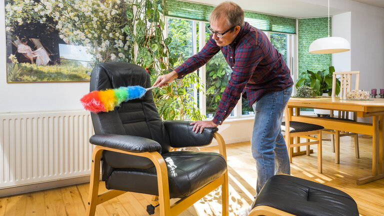 mand rengør læderstol med støvkost