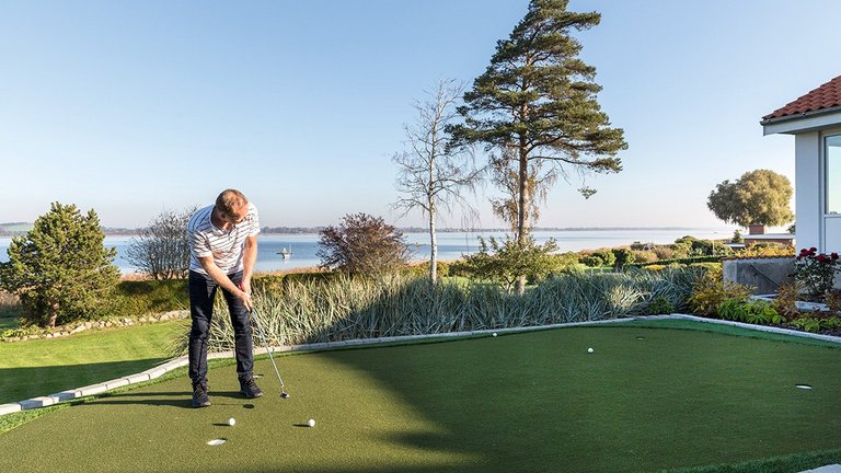 Udsigt til vand og egen golfbane med putting green i egen have