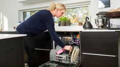 Kvinde sætter beskidt tallerkner i opvaskemaskinen