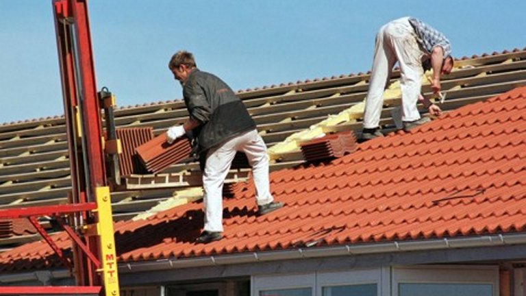 Håndværkere lægger nyt tag på hus