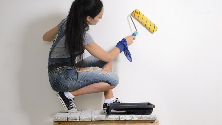 Kvinde maler væg i lejlighed, før hun flytter ud