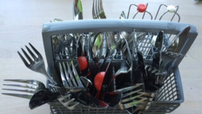 Bestik i bestikkurv i opvaskemaskine med skaftet ned