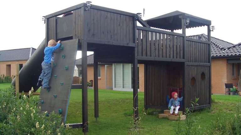 Børn leger i legetårn i privat have