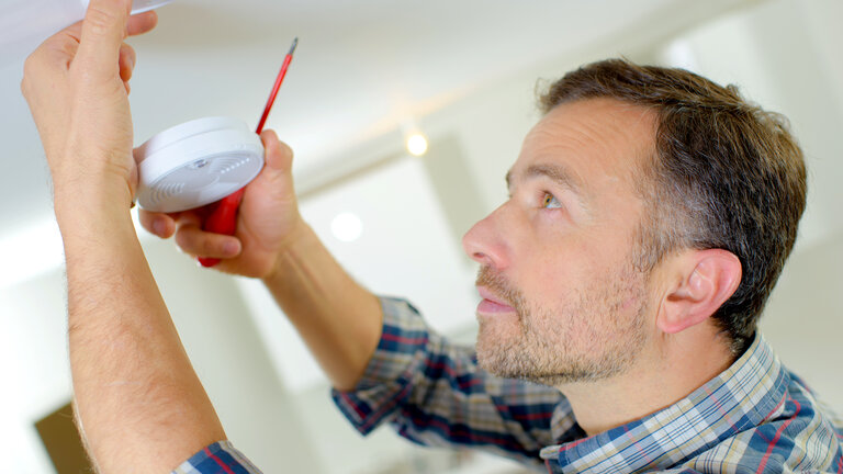 mand sætter røgalarm op