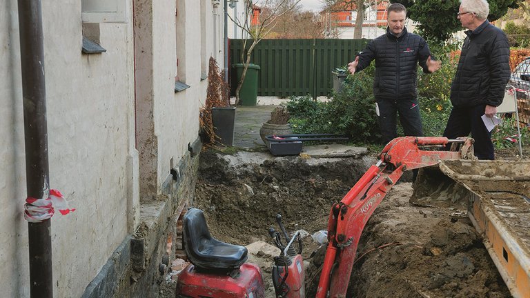To byggerådgivere står foran hus, der er i gang med stor renovering