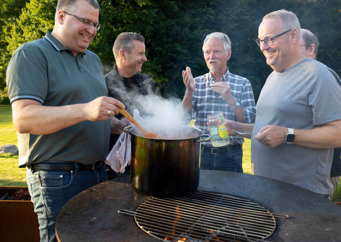 Fem mænd omkring en grill