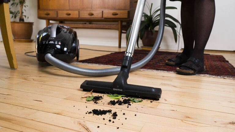 Støvsuger jord og planterester op fra trægulv