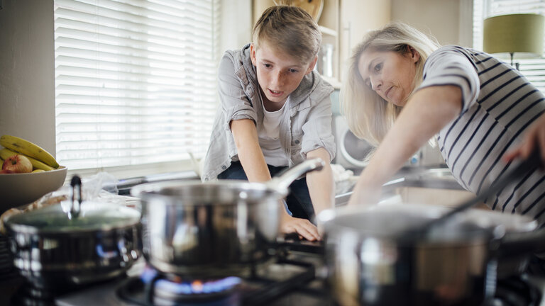 Mad koger i gryder på komfur uden låg og tændt emhætte