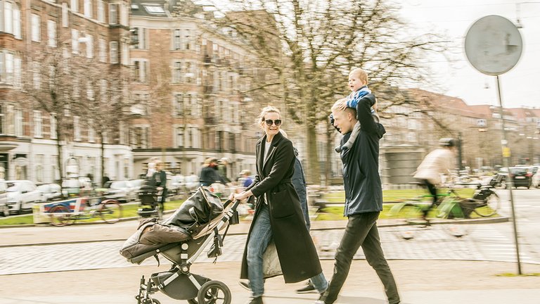 Ungt par går tur med deres barn i dansk by