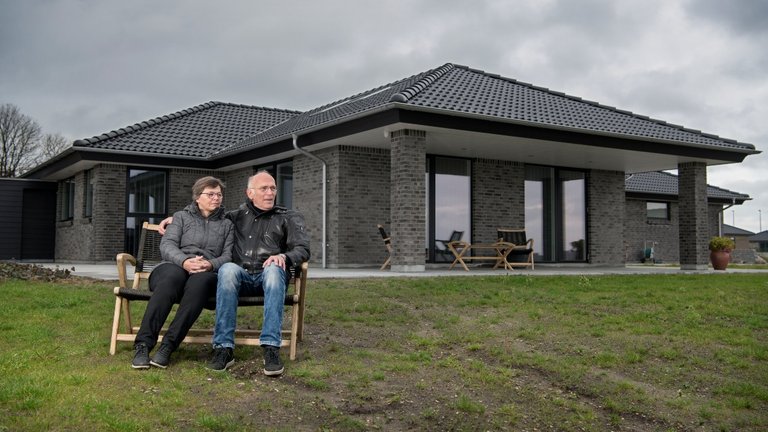 Henning og Metha sidder på en bænk foran deres hus