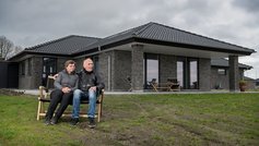 Henning og Metha sidder på en bænk foran deres hus