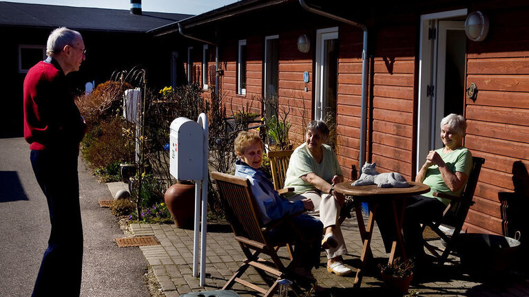 Ældre i samtale foran rækkehuse
