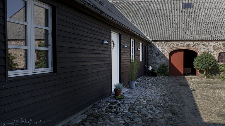 Kampestensgård med moderne tilbygning i træ