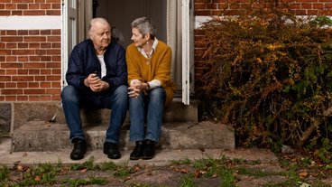 Abelone og Peter sidder på trappetrin foran hus