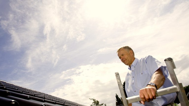 Mand tjekker tag for skader og utætheder