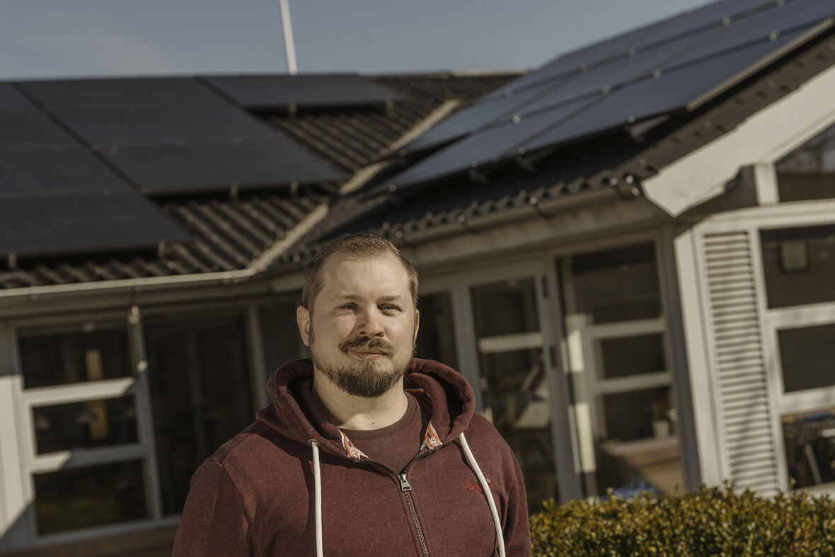 Nicholas Elfang foran sit hus med solceller på taget