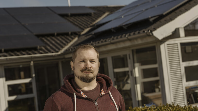 Ejeren foran sit hus med solceller på taget