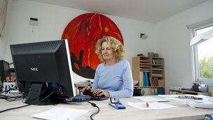 Kvinde sidder foran sin pc ved hjemmearbejdsplads