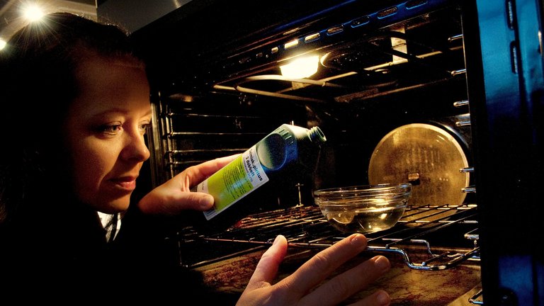 Kvinde hælder salmiakspiritus i en glasskål, der står i en ovn.