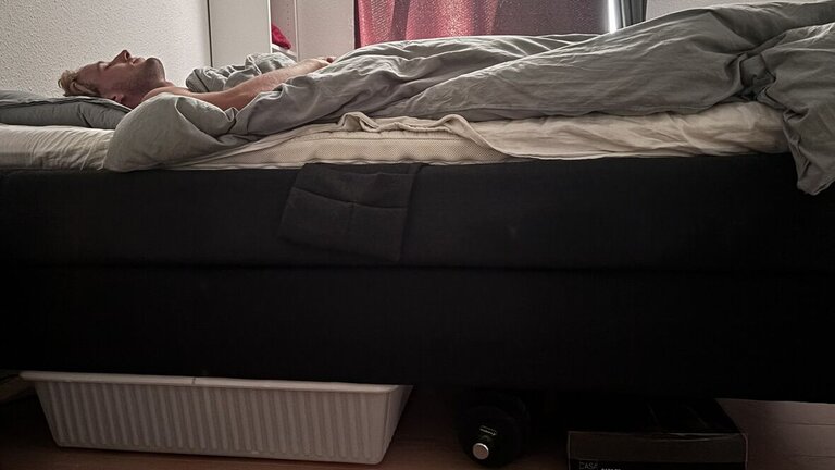mand sover med ting under sengen i soveværelse