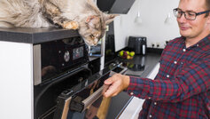 mand åbner ovnlåge efter madlavning