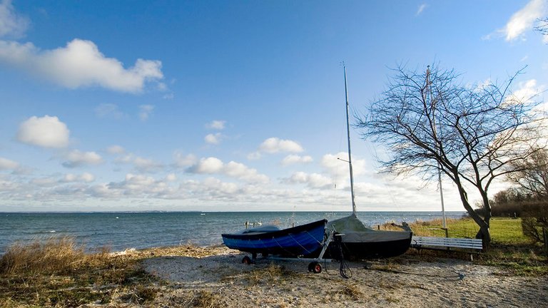 Båd ligger i sandet på privat strand. På mange private strande er der ulovlige skræmmeskilte, der skal holde andre væk, selv om de har lovlig adgang
