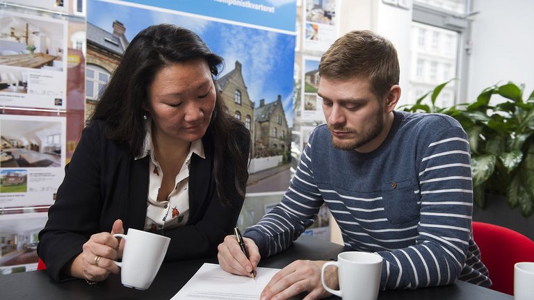 Mand og kvinde underskriver købsaftale