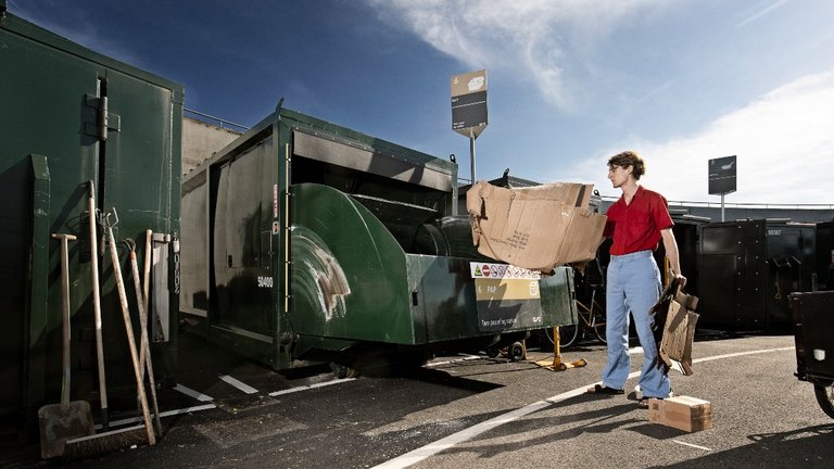 Mand smider pap i container