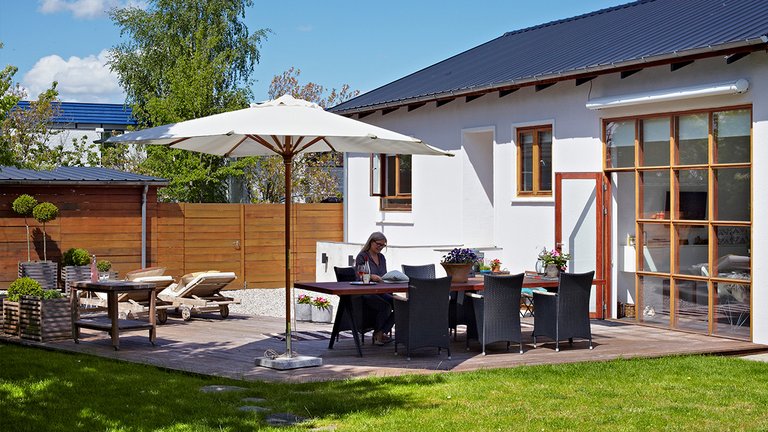 Anne Marie sidder i haven foran sit hus